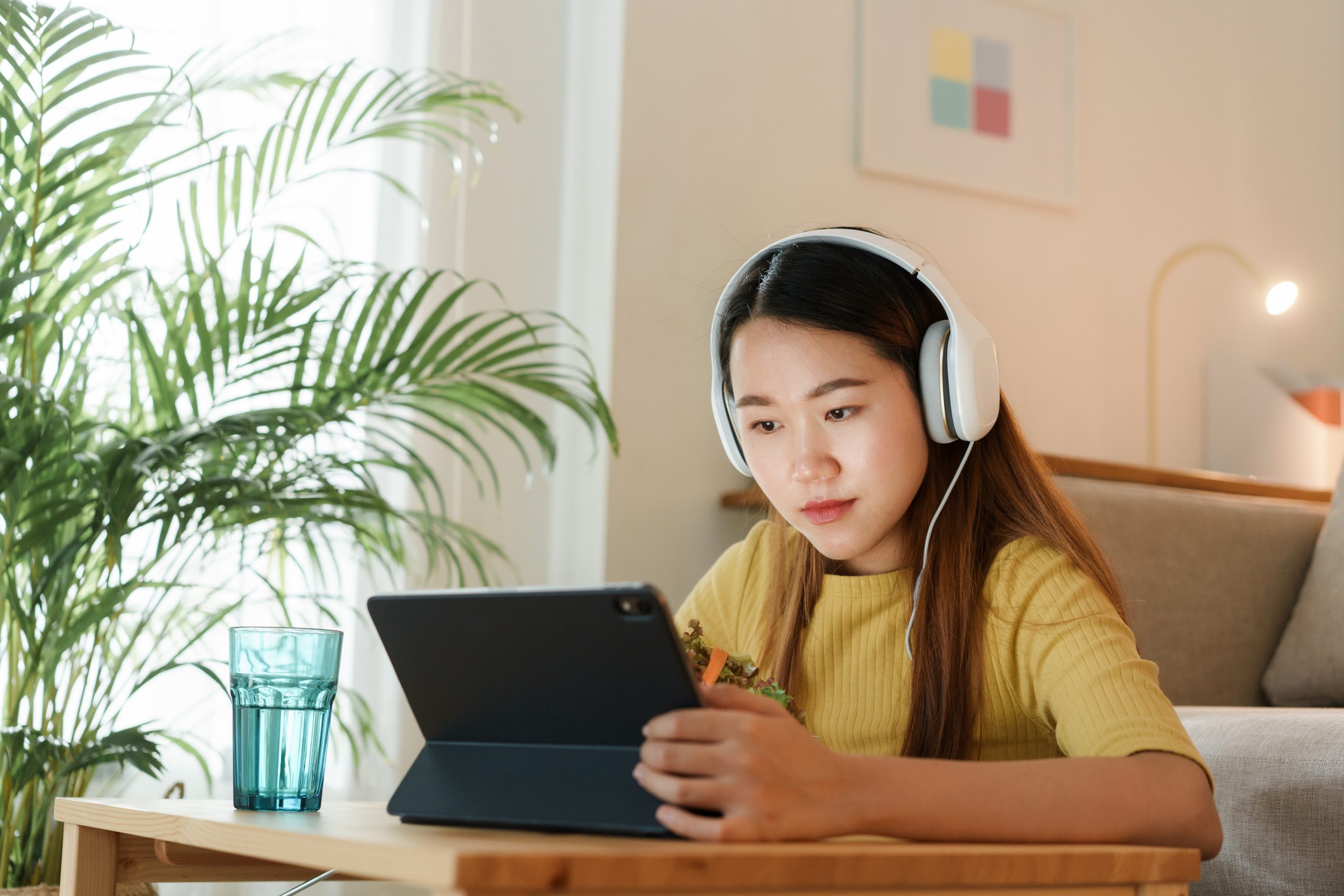 beautiful Asian young woman using a tablet and eat salad for lun