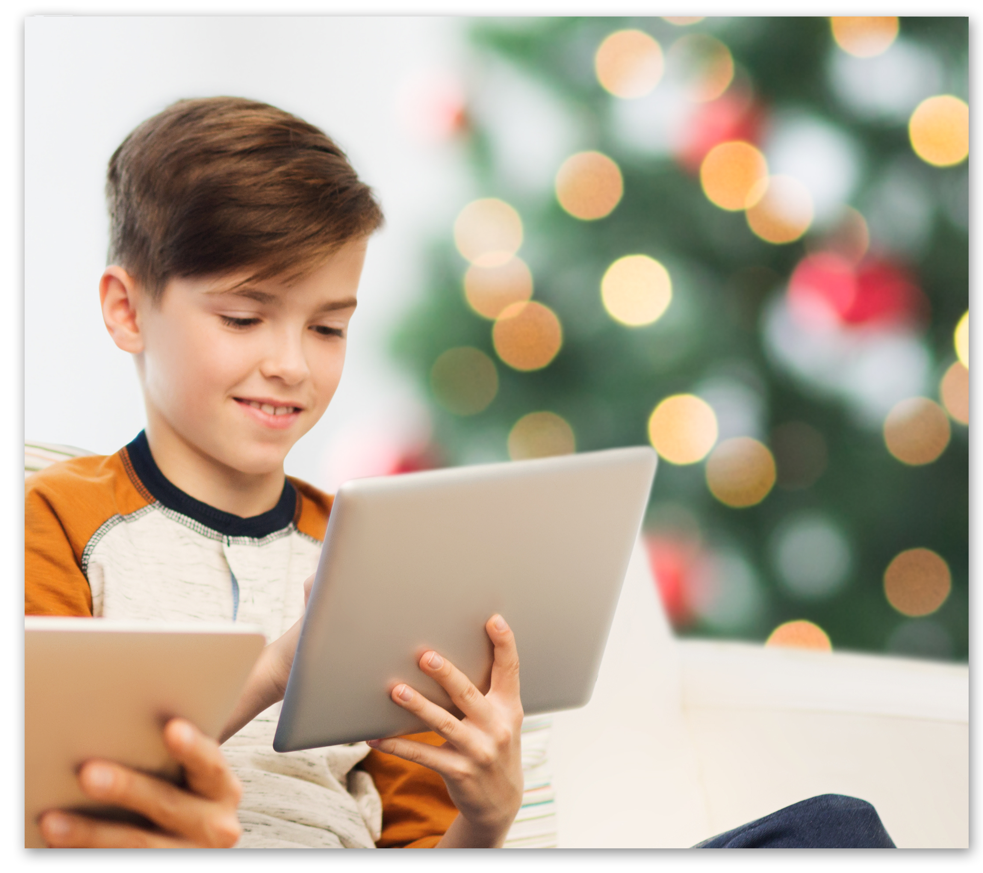 Boy holding laptop in front of christmas tree