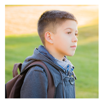 young boy going to school with backpack on