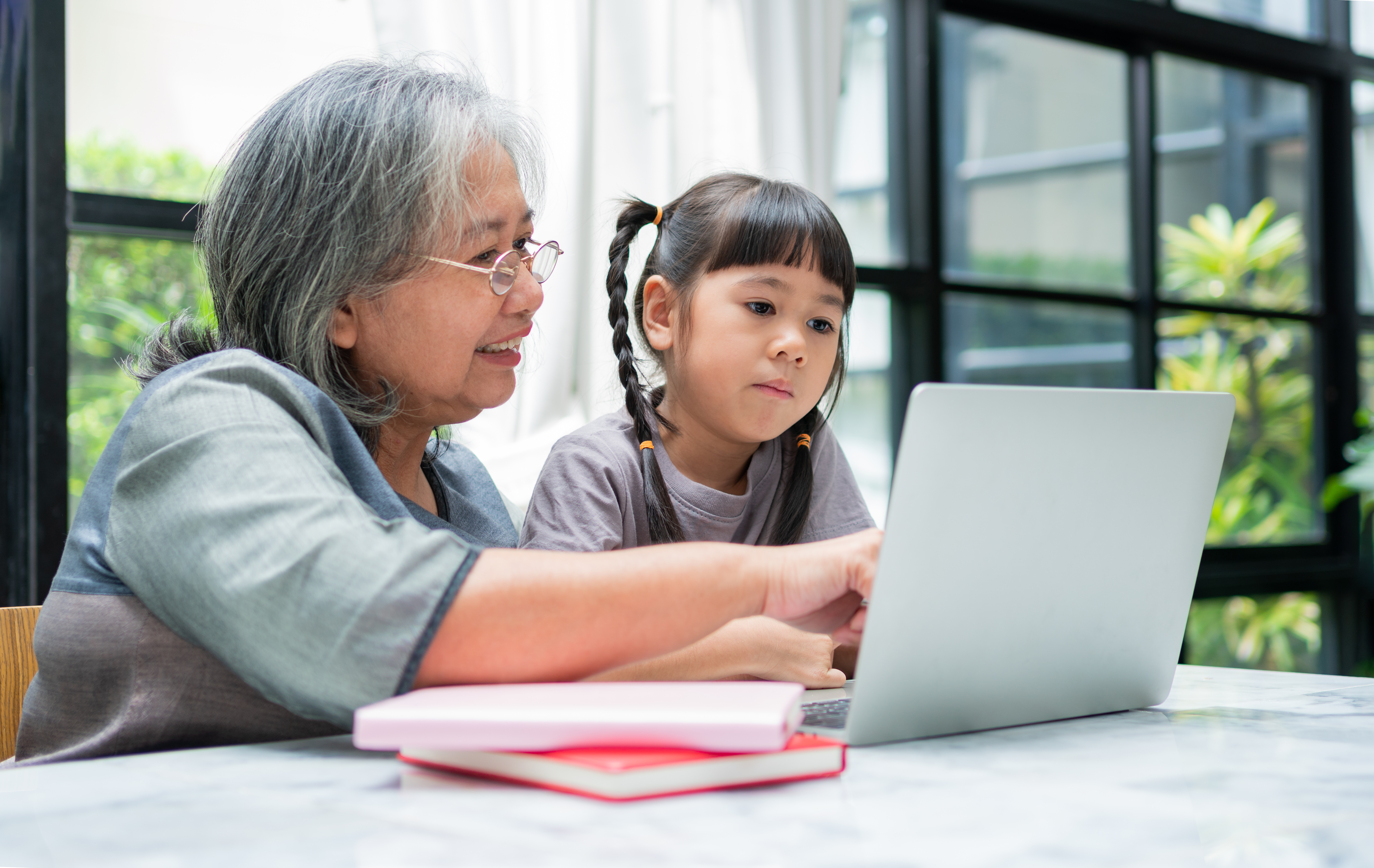 grandmother helping young K-5 student with homework on laptop