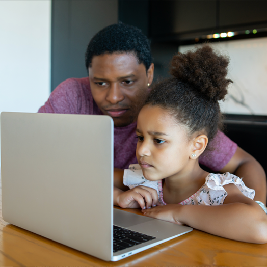 Parent working with young student on digital courses using a laptop