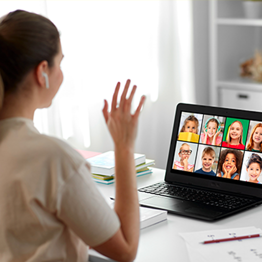 Teacher waving to K-12 students as she teaches remotely